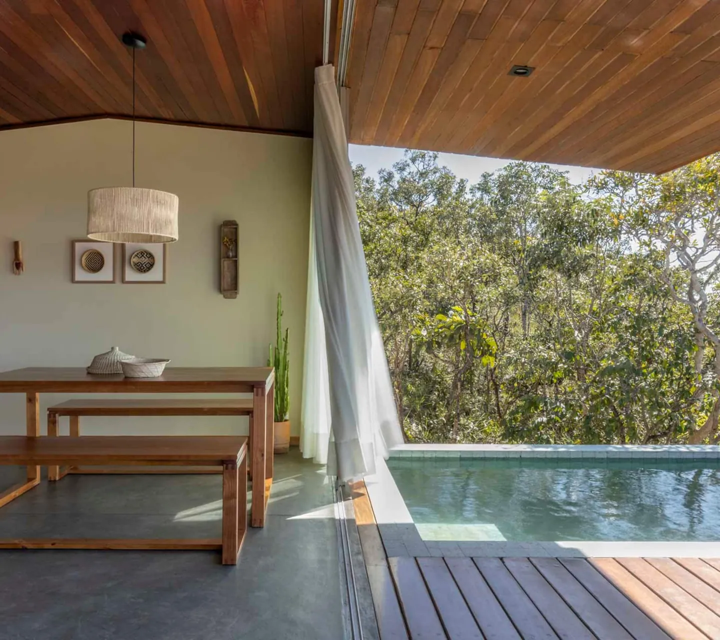 Mesa de jantar da Casa Ipê aberta para o deck e a piscina