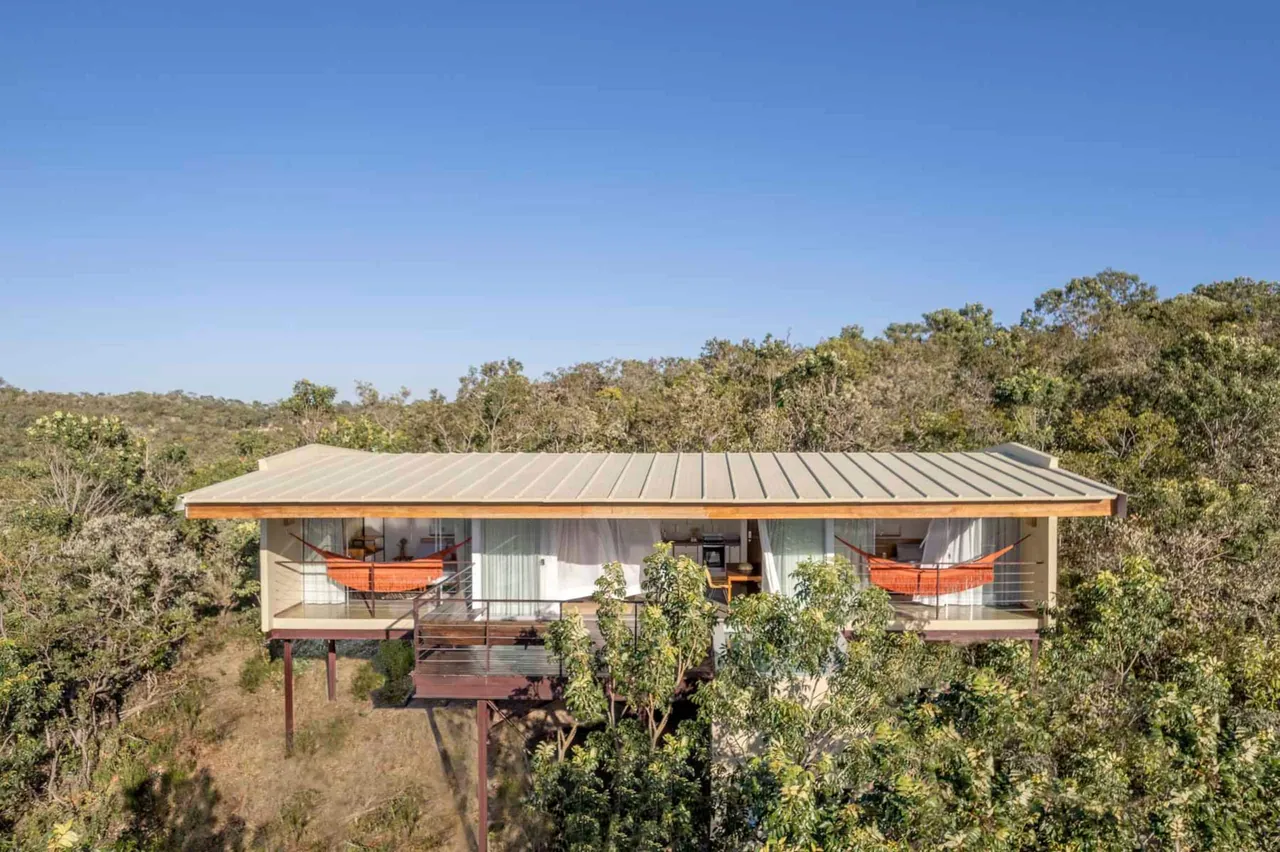 Casa Jacarandá sobre pilotis, com redes na varanda, em meio ao cerrado